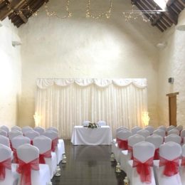 Dunster Tythe Barn Wedding Room with Red bow chairs 260x260