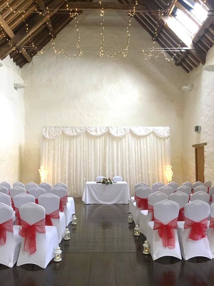 Dunster Tythe Barn Wedding Room with Red bow chairs