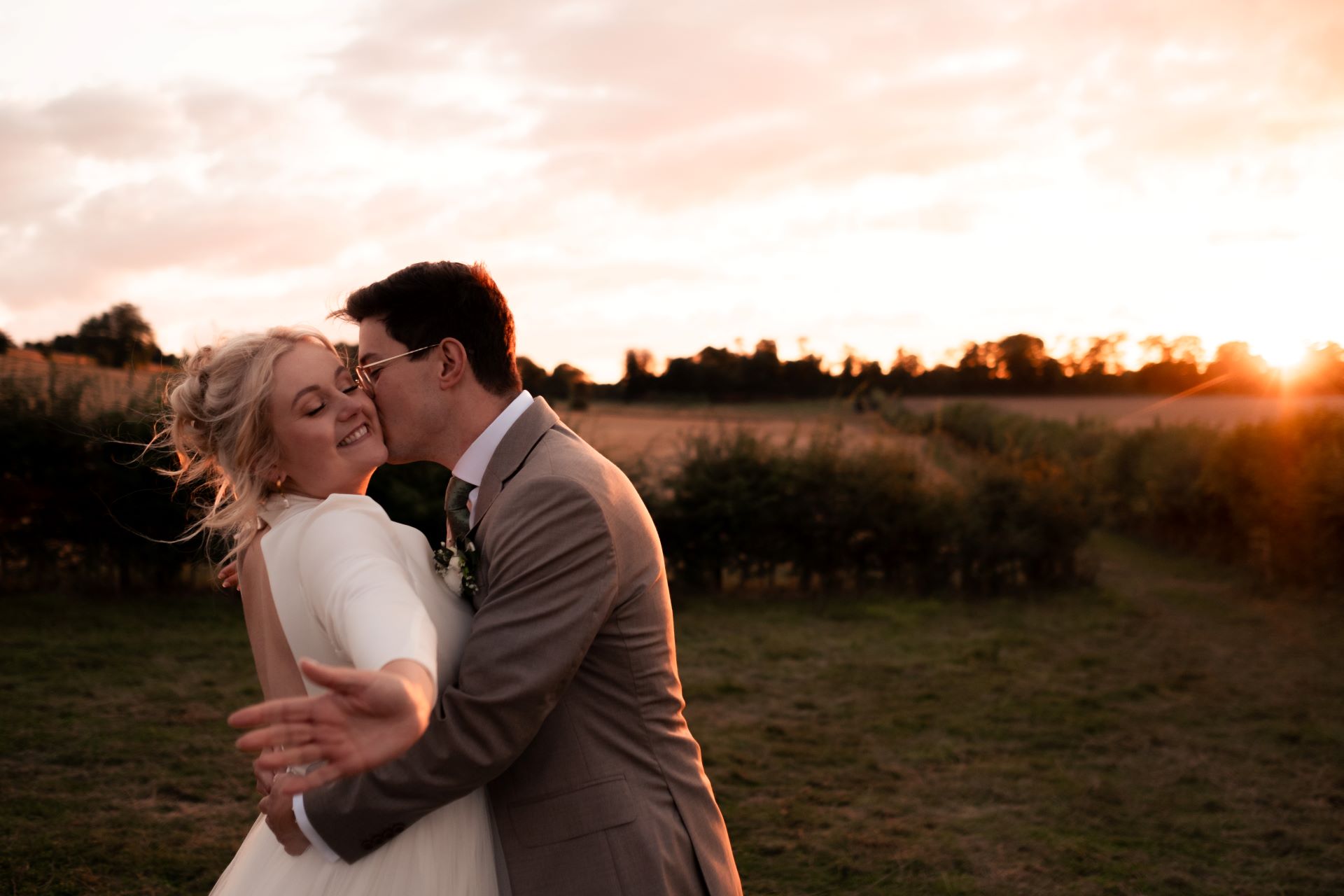 bride smiles groom kisses cheek sunset oxfordshire.jpg